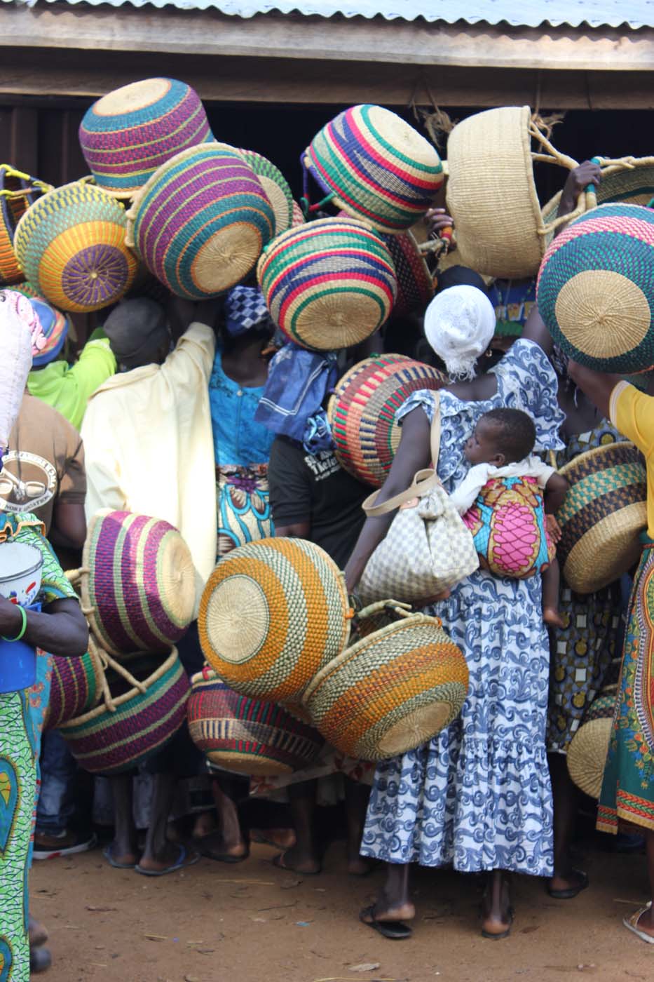 A throng of weavers and villagers offer up their baskets to sell